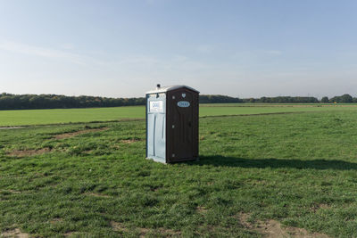Portable toilet on field against sky