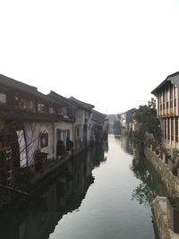 Reflection of buildings in city against clear sky