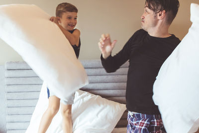 Father and son pillow fighting at home