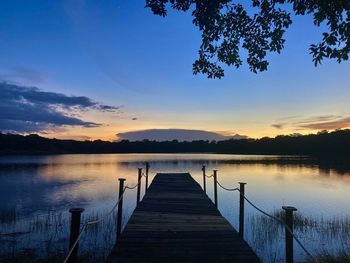 Wooden pier over lake against sky during sunset