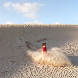  boy sliding down dune
