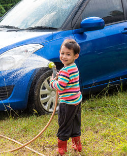 Portrait of cute boy washing car outdoors