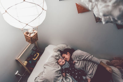 High angle view of mother and son lying on bed at home