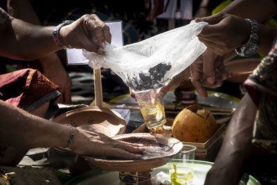 Midsection of men with drink and container at market