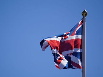 Low angle view of british flag against waving against clear blue sky