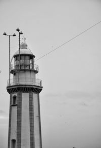 Low angle view of lighthouse by building against sky