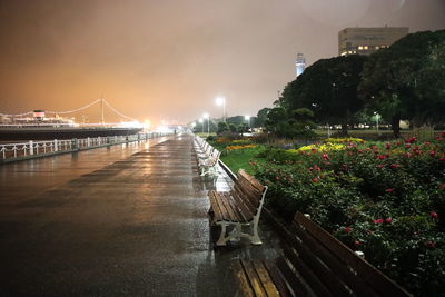 Illuminated bridge over river in city against sky at night