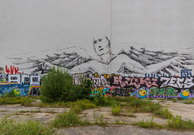 Graffiti on wall by building in city against sky