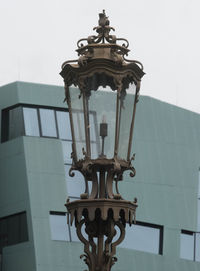 Low angle view of electric lamp on building against sky