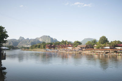 Scenic view of river by buildings against sky