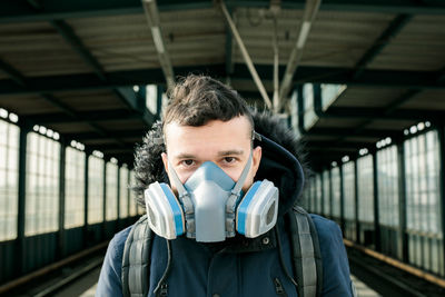Portrait of young man at railroad station with mask on 