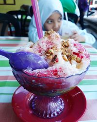 Close-up of ice cream on table with girl in background at restaurant