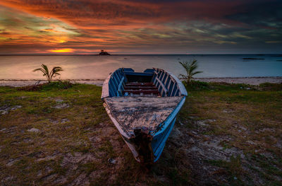 Boat moored at sea shore during sunset