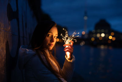 Young woman holding illuminated string light at night
