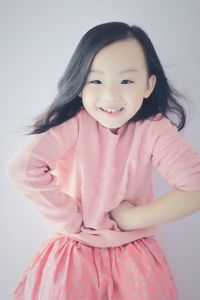 Portrait of smiling girl standing against pink background