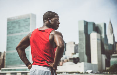 Young man looking away against buildings in city