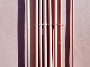 Set of pink vertical water piping against pink wall