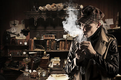 Man smoking pipe while standing against antiques in storage room