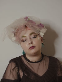 Portrait of young woman standing against wall