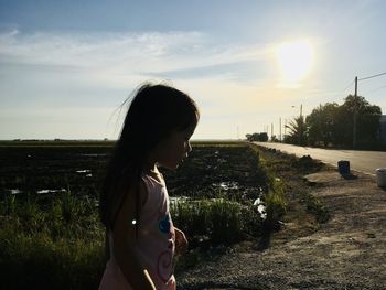 Woman standing on field against sky during sunset