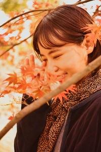 Side view of young woman holding autumn leaves