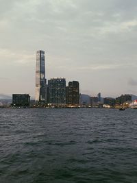 Sea by modern buildings in city against sky