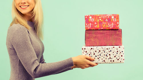 Midsection of woman holding umbrella against gray background