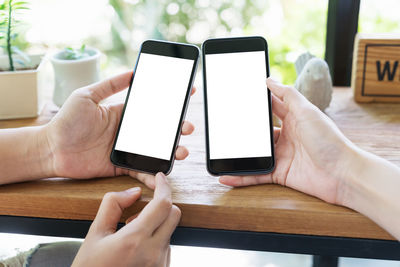 Midsection of person holding mobile phone on table