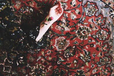 Cropped hand of woman lying on rug