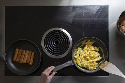 Overhead view of someone cooking scrambled eggs and sausage