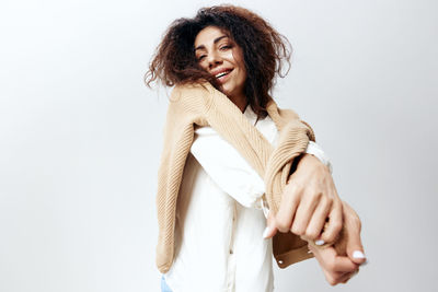 Portrait of young woman standing against white background