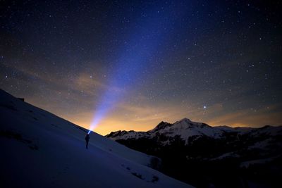 Scenic view of snowcapped mountains against sky at night