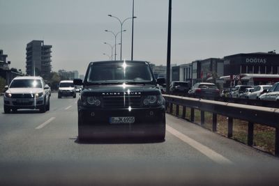 Cars on road against sky in city