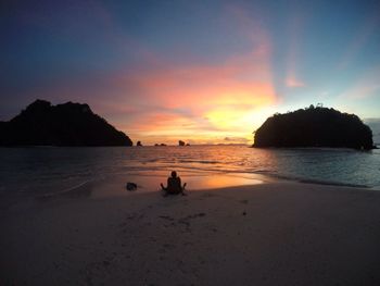 Silhouette man on beach against sky during sunset