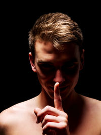 Close-up portrait of shirtless man against black background