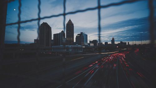 Light trails on road in city against sky