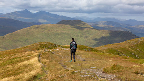 Rear view of man standing on mountain against sky