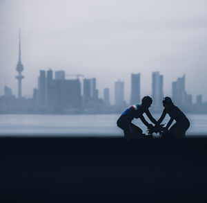2 woman elite cyclists from kuwait team preparing for time trial race. and cityscape in the ba