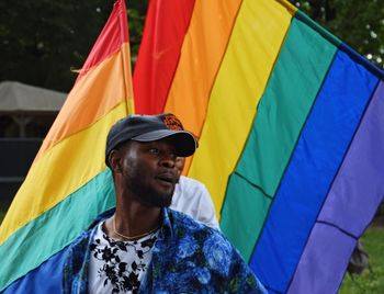 Portrait of smiling man standing against multi colored umbrella