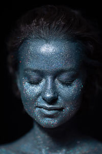 Portrait of a woman with a blue face in glitter