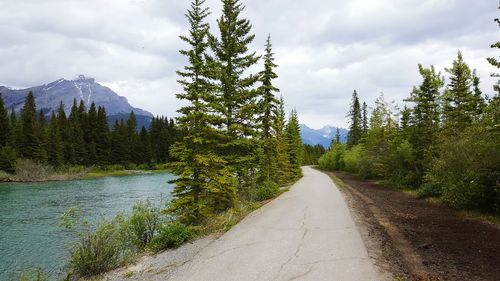 Road by river against mountains and sky