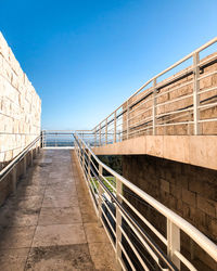 Empty footpath against clear blue sky