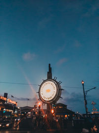 Low angle view of illuminated clock tower against sky at dusk