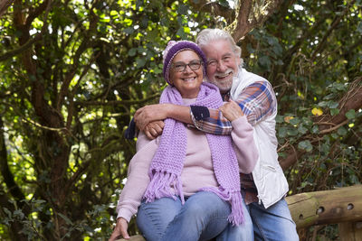 Portrait of a smiling couple sitting on tree