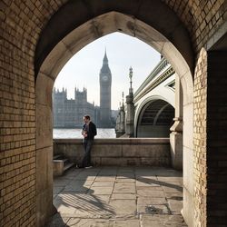 Young man standing on promenade by thames river against big ben