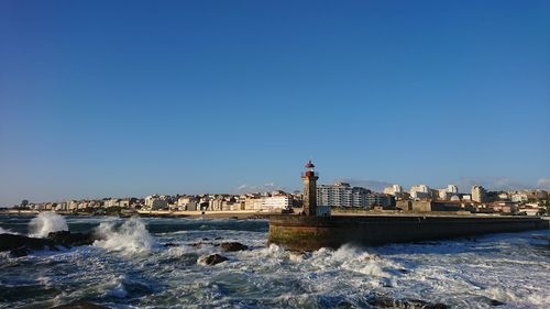Sea by buildings against clear blue sky