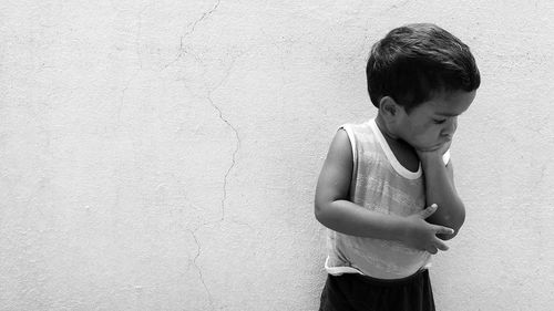 Thoughtful boy standing against wall