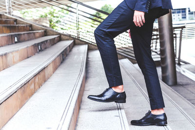 Low section of businessman walking on staircase