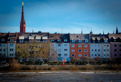 Buildings at waterfront against cloudy sky