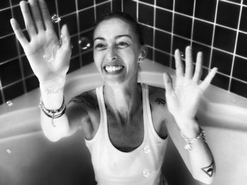 High angle view of cheerful woman playing with bubbles in bathtub